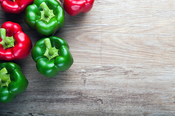 Fake red and green peppers on wooden board background with copy space