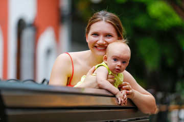 Portrait of happy mother sitting on a bench with her baby girl