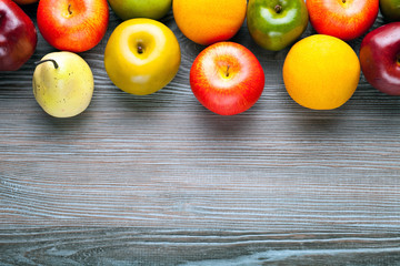 Apples pears and oranges on wooden board background with copy space
