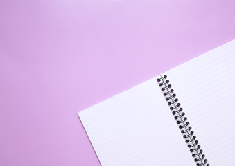 A blank lined notebook laid open on a pink background