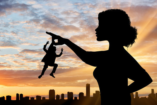 Silhouette feminist holds in his hand the little man against the backdrop of the cityscape