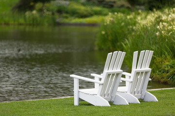 weiße Gartensessel am See