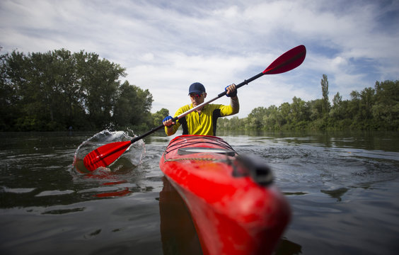 A man paddles a red kayak.