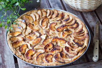 Delicious apple pie with sour cream and cinnamon on old wooden table