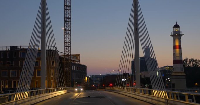 Car driving across the city bridge in late evening, logos washed out. View to the city and lighthouse. Malmo, Sweden