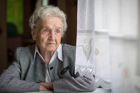 Elderly woman portrait, sitting in the house.