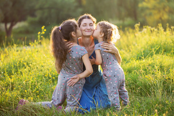 Fototapeta premium Children kissing mother outdoors.