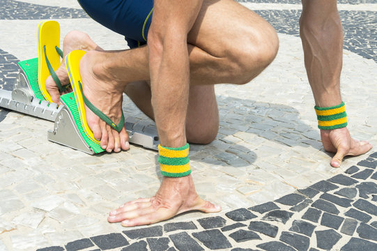 Brazilian Athlete Wearing Flip Flops Crouching At The Start Position In Running Blocks On The Tiles Of The Copacabana Boardwalk In Rio De Janeiro, Brazil