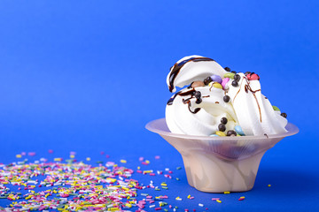 frozen yogurt with chocolate and chocolate candy topping on blue background with rainbow sprinkles