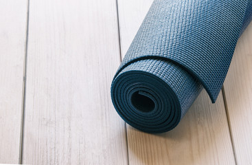 Dark blue mat for yoga, pilates or fitness on wood background. Space for text.Vintage style.