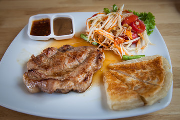 Pork steak with roti and Thai papaya salad.