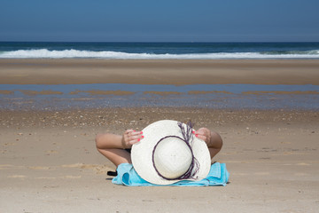 Fototapeta na wymiar Girl lies on the white sand on the beach symbol of holidays