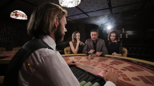 The rich man surrounded by two prostitutes to play and win at the casino