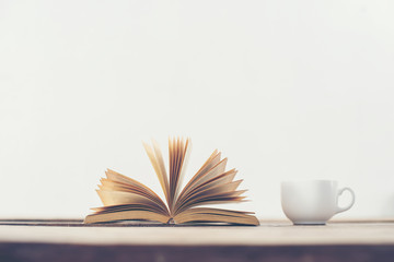 Vintage old book with coffee cup on wooden deck table background