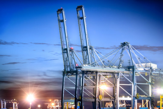Port cranes working in shipyard at dusk for Logistic Import Export background
