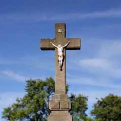 Old figure Christ on the stony cross at cemetery, stony crucifix