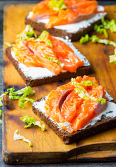Sandwich with cereals black bread and salmon on wooden board background
