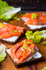 Sandwich with cereals black bread and salmon on wooden board background