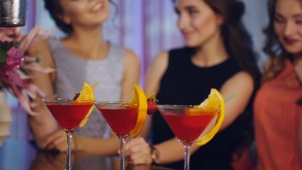 beautiful girl watching with delight as the barman prepares them for cocktails