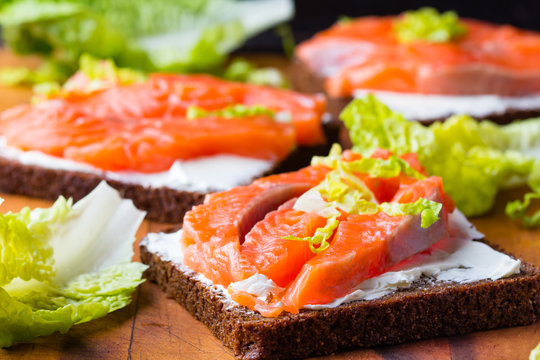Sandwich with cereals black bread and salmon on wooden board background