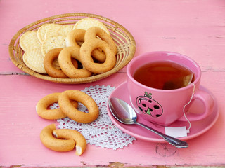 cup of tea, bagels and cookies on a pink background