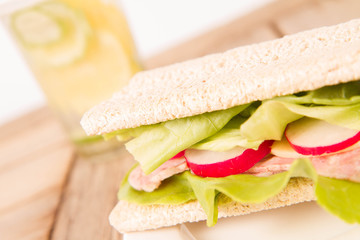 Crispbread sandwich with headcheese, cheese, radish and lettuce and a glass of lemonade