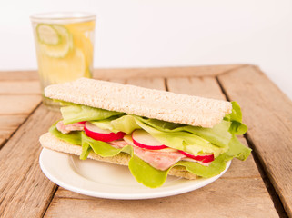 Crispbread sandwich with headcheese, cheese, radish and lettuce and a glass of lemonade