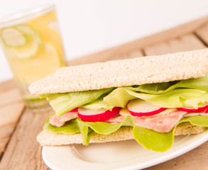 Crispbread sandwich with headcheese, cheese, radish and lettuce and a glass of lemonade