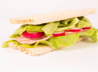 Crispbread sandwich with headcheese, cheese, radish and lettuce on a white background