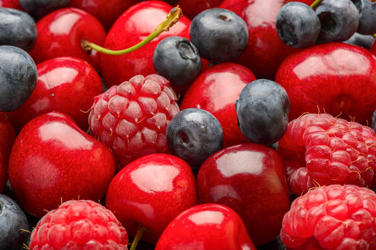 Ripe summer berries (blueberries, raspberries and cherries) as background.