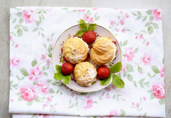 Cream puffs or profiterole filled with whipped cream, powdered sugar topping served with strawberries