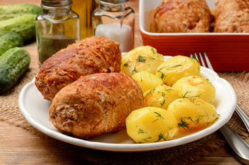 Roasted meat roulades sereved  with baked potatoes. On wooden background.