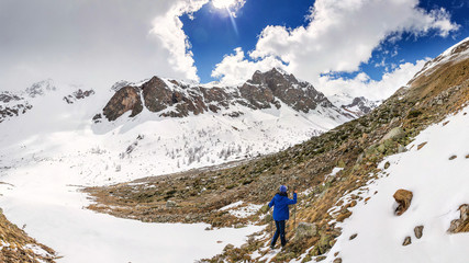 tourist hiker walking in mountains near the snowfield and glacier. Offseason trekking concept