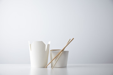 Opened and closed takeaway boxes for chinese noodles presented with chopsticks, isolated on white...
