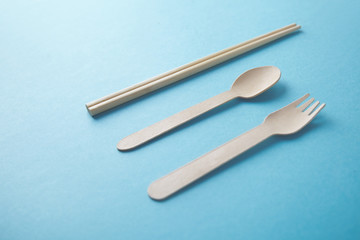 Kitchen utencils set for takeaway business: wooden recycling eco spoon, fork and chopsticks isolated on turquoise side view