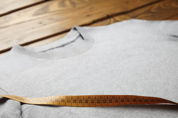 Close view blank grey t-shirt on wooden table with tailor ruler on it