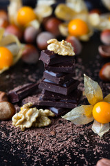 Chocolate, nuts, golden berries physalis on black background