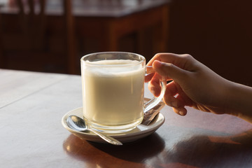 woman is holding a cup of fresh milk with blurry background