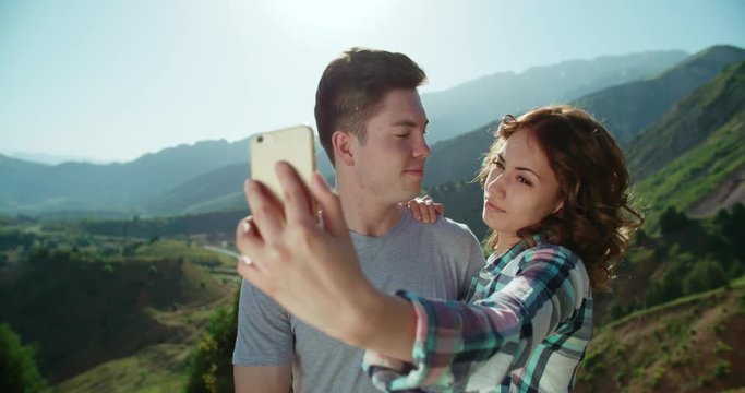 Smart phone selfie - couple taking self portrait using smartphone camera in the background mountains sunset time,slow motion