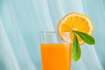 Fresh squeezed orange juice with sliced oranges and green leaf with sea on a background. Healthy drink in the morning.