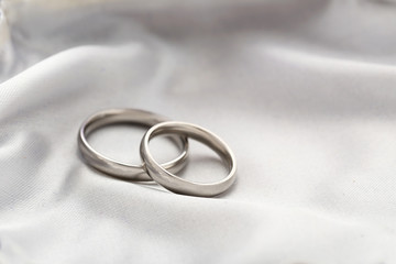 Silver wedding rings on a white satin