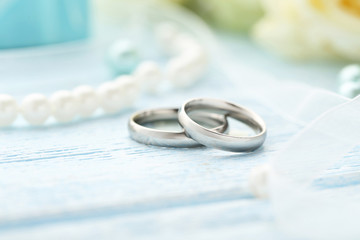 Silver wedding rings on a blue wooden table