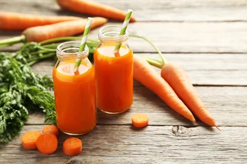 Crédence de cuisine en verre imprimé Jus Fresh carrot juice in bottles on a grey wooden table