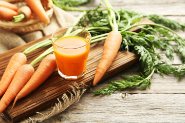 Fresh carrot juice in glass on a grey wooden table
