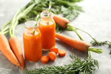 Fresh carrot juice in bottles on a grey background