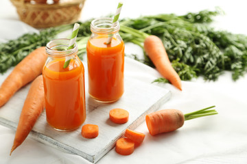 Fresh carrot juice in bottles on a white wooden table