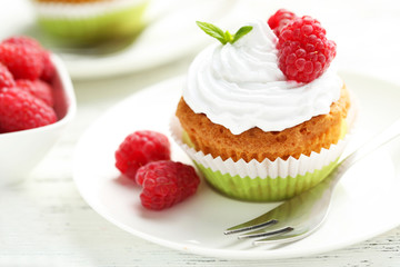 Raspberry cupcakes on plate on white wooden background
