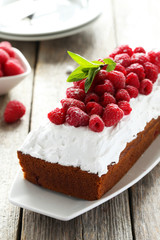 Raspberry cake on plate on white wooden background