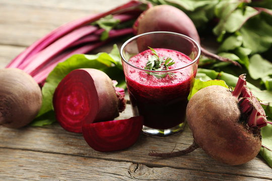 Fresh beets juice in glass on a grey wooden table