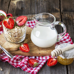 Oat flakes, milk, strawberries for breakfast on a gray wooden background
